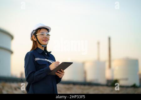 Asiatische Frau petrochemische Ingenieur arbeitet mit digitalen Tablette in Öl-und Gasraffinerie-Fabrik Industrie Fabrik in der Nacht für Inspektor Sicherheit Qualität Stockfoto