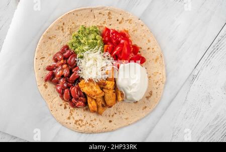 Taco mit Hühnchen- und Gemüsefüllung auf dem Holzhintergrund Stockfoto