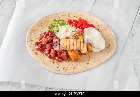 Taco mit Hühnchen- und Gemüsefüllung auf dem Holzhintergrund Stockfoto