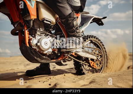 Fahrer beim Motocross-Rennen. Schwerpunkt auf Hinterrad mit Gleitkufe. Biker im Parcours mit staubiger Piste Stockfoto