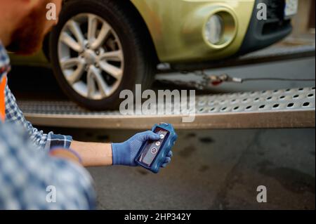 Nahaufnahme eines männlichen Straßenarbeiters, der eine einheitliche Überwachung des Ladeprozesses des Fahrzeugs auf der Evakuierungsplattform trägt Stockfoto