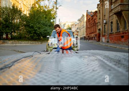 Mann Mechaniker Straßenarbeiter Vorbereitung Abschleppwagen Plattform für die Autoladung Stockfoto