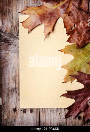 Vintage-Papier und Herbstlaub auf hölzernen Hintergrund Stockfoto