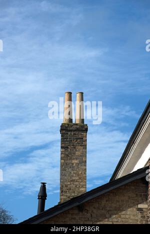 Twin Chimney auf Ziegelchimneystack zeigt auch Heizungslüfter und Dachlinien Stockfoto