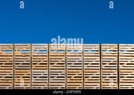 Leere Paletten vor blauem Himmel gestapelt Stockfoto