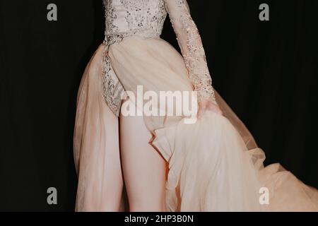 Weibliche Figur in einem üppigen Abendkleid in Beige auf schwarzem Hintergrund Stockfoto