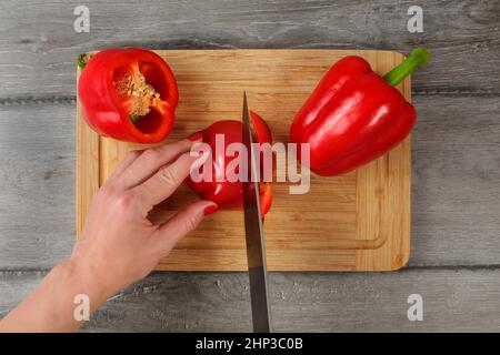 Table Top Aussicht, Frau schneiden Paprika mit Chefs Messer auf Schneidebrett. Stockfoto