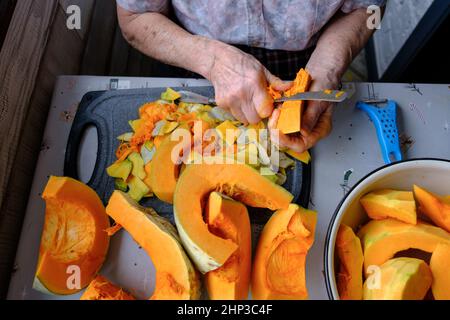 Alte Frau schneidet und Pillen gelben Kürbis, Kochen Kürbissuppe, Ruhestand Leben, selektive Konzentration Stockfoto