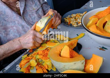 Alte Frau schneidet und Pillen gelben Kürbis, Kochen Kürbissuppe, Ruhestand Leben, selektive Konzentration Stockfoto