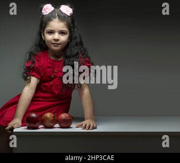 Kleines Mädchen mit drei Granatäpfeln vor ihr. Happy yalda iranische Feier Thema Stockfoto