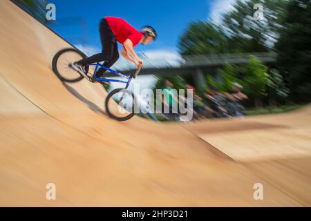 BMX-Fahrer springt auf einer U-Rampe in einem Skatepark über (Bewegungsunschärfe) Stockfoto