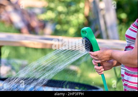 Pflanzen in der Hitze mit einem Schlauch gießen. Hochwertige Fotos Stockfoto