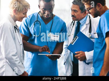 Intelligente Technologie macht die Patientenversorgung intelligenter. Aufnahme eines Ärzteteams, das zusammen ein digitales Tablet in einem Krankenhaus verwendet. Stockfoto