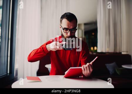 Mann mit Notizbuch trinkt in der Pause Tee Stockfoto