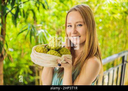 Cherimoya in einer wiederverwendbaren Tasche in weiblichen Händen. Null-Abfall-Konzept, plastikfreies Konzept. Gesunde, saubere Ernährung und Entgiftung. Sommerfrüchte Stockfoto