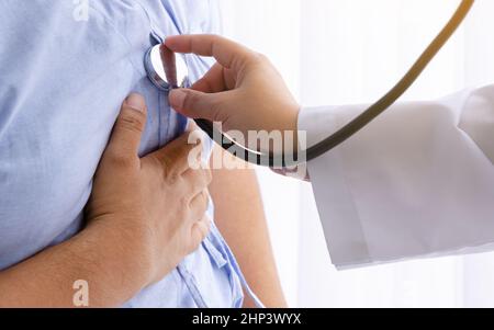 Ärztin, die im Krankenhauszimmer ein Stethoskop verwendet, um den Herzschlag eines männlichen Patienten mit Herzinfarkt zu hören Stockfoto