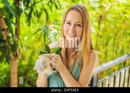 Avocado in einer wiederverwendbaren Tasche in weiblichen Händen. Null-Abfall-Konzept, plastikfreies Konzept. Gesunde, saubere Ernährung und Entgiftung. Sommerfrüchte Stockfoto