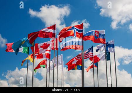 Leuchtende Flaggen verschiedener Länder gegen den blauen Himmel und Wolken Stockfoto