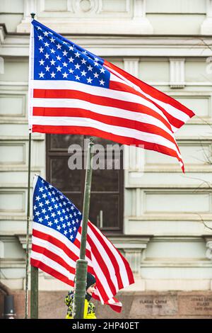 Amerikanische Flaggen, die mit einem Teil eines Militärfahrzeugs und Kind oder Kind darauf verzichten, vertikal Stockfoto