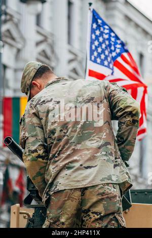 US Marine Corps Soldat auf der Oberseite eines Militärfahrzeugs Montage eines Maschinengewehrs mit amerikanischer und litauischer Flagge, USA oder US-Armee, vertikal Stockfoto