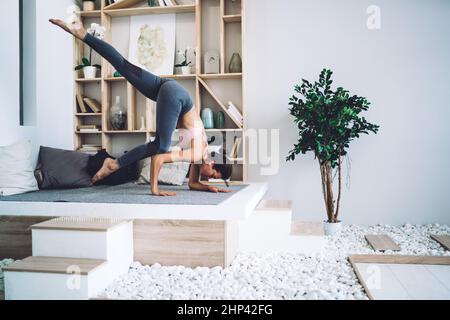 Junge schlanke Brünette tun schwer Arm stehen Asana während Yoga-Training Stockfoto