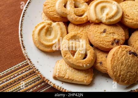 Dänische Butterkeks auf einem weißen Teller. Haufen von verschiedenen knusprigen Shortbread-Keksen aus der Nähe. Gebackenes Gebäck zum Frühstück. Leckerer Snack. Süßes Essen. Stockfoto