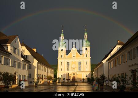 Arlesheimer Dom nach einem Gewitter. Der Himmel ist dunkel mit einem Regenbogen direkt über der Kuppel, die Abendsonne erleuchtet die Kathedrale. Arlesheim Stockfoto