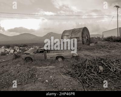 Verlassene Auto mit Ölfass Stockfoto