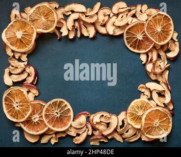 Rahmen aus getrockneten Apfel- und Orangenscheiben auf blauem Hintergrund mit Kopierraum Stockfoto