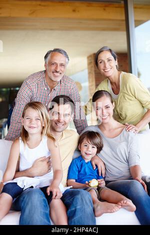 Drei Generationen der Liebe. Ein Porträt einer glücklichen, generationsübergreifenden Familie, die sich zu Hause in ihrem Wohnzimmer versammelt hat. Stockfoto