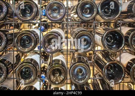 Wein in einem Metallregal - Ansicht der Flaschenböden einer Vielzahl von Marken - selektiver Fokus Hintergrund Stockfoto