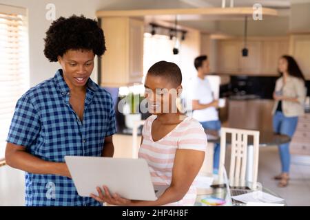 Junge geburtssichliche Geschäftsfrau und Geschäftsfrau diskutieren über Laptop mit Kollegen Stockfoto