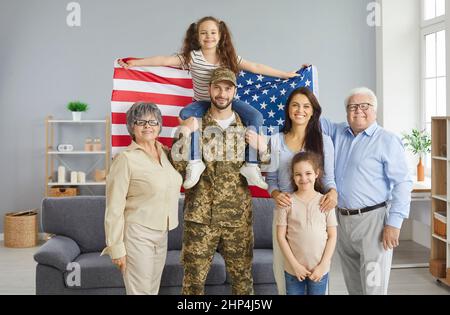 Porträt eines Militärvaters und seiner großen glücklichen Familie mit einer amerikanischen Flagge in den Händen. Stockfoto