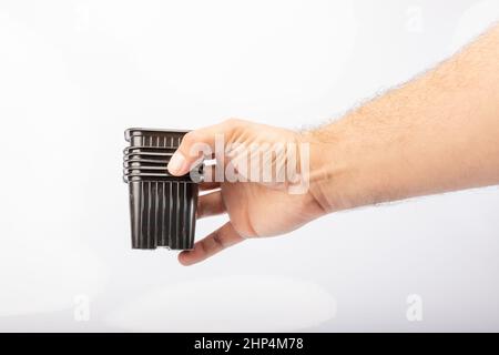Hand hält Pflanztöpfe auf weißem Hintergrund im Studio Stockfoto