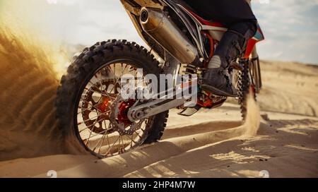 Fahrer beim Motocross-Rennen. Schwerpunkt auf Hinterrad mit Gleitkufe. Biker im Parcours mit staubiger Piste Stockfoto