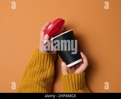 Hände halten braune Pappbecher für Kaffee. Umweltfreundliches Geschirr Stockfoto