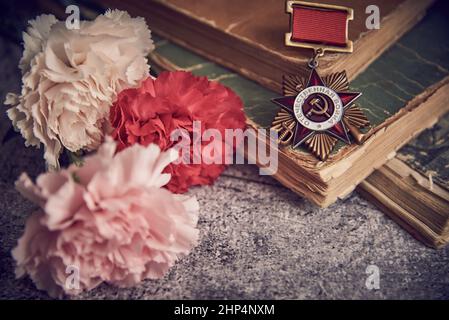 Victory Day Mai 9 Feiertagshintergrund Komposition, sowjetischer Orden mit russischem Text, übersetzt ins Englische als Patriotischer Krieg, zweiter Weltkrieg, Bücher, Auto Stockfoto