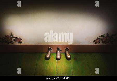 Nahaufnahme auf aufrechten Piano-Fußpedalen auf grünem Holzboden. Stockfoto