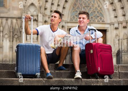 Paar Touristen, die an der Treppe mit Karte und Gepäck sitzen Stockfoto