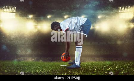 Fußballszene bei Nacht Spiel mit Spieler in weiß und Uniform Platzierung der Ball zu treten Stockfoto