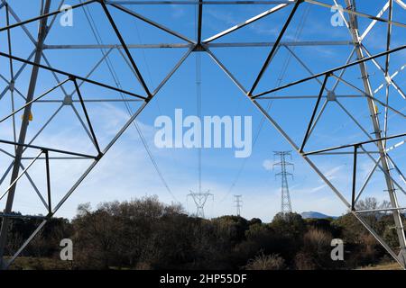 Closeup unter Ansicht von hoch aufragenden Stahl-Pylon tragenden Stromkabel am blauen Himmel Stockfoto