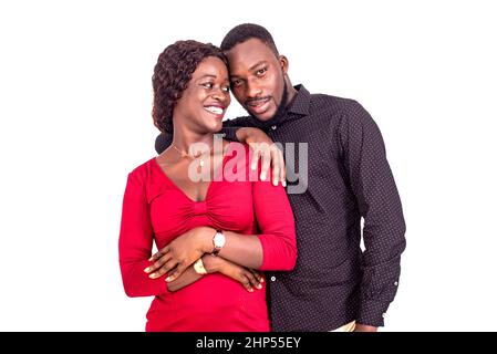 Junges afrikanisches Paar, das auf weißem Hintergrund steht und lächelnd umarmt. Stockfoto