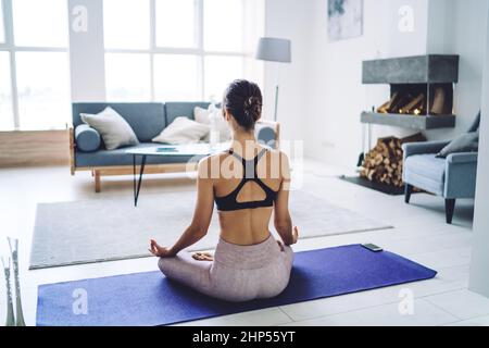 Junge gesichtslose, fittige Sportlerin, die morgens meditiert Stockfoto