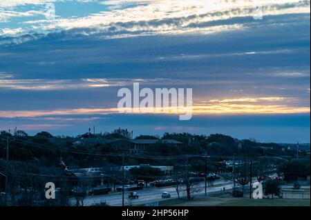 Austin, Texas, USA. 18. Februar 2022. Austin erwacht zu eiskalten Temperaturen. Sonnenaufgang auf dem Murchison Hill im Nordwesten von Austin, während Menschen, die sich für kaltes Wetter kleiden, ihren Weg zur Arbeit finden. . Kredit: Sidney Bruere/Alamy Live Nachrichten Stockfoto