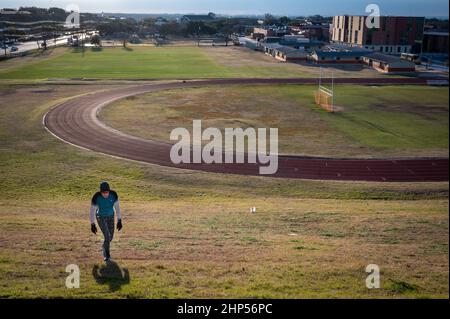 Austin, Texas, USA. 18. Februar 2022. Ein Läufer klettert den Hügel nach seinem morgendlichen Lauf an der Mittelschule von Murchison. Austin erwacht zu eiskalten Temperaturen. Sonnenaufgang auf dem Murchison Hill im Nordwesten von Austin, während Menschen, die sich für kaltes Wetter kleiden, ihren Weg zur Arbeit finden. . Kredit: Sidney Bruere/Alamy Live Nachrichten Stockfoto