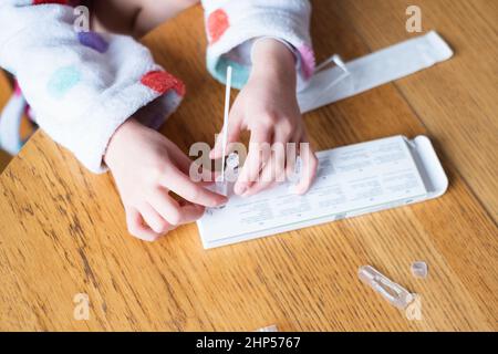 Kind testet sich zu Hause auf Coronavirus. Rapid COVID-19 Antigen Testkit für Selbsttests. Stockfoto