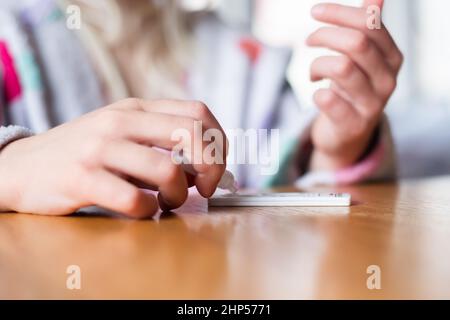 Kind testet sich zu Hause auf Coronavirus. Rapid COVID-19 Antigen Testkit für Selbsttests. Stockfoto