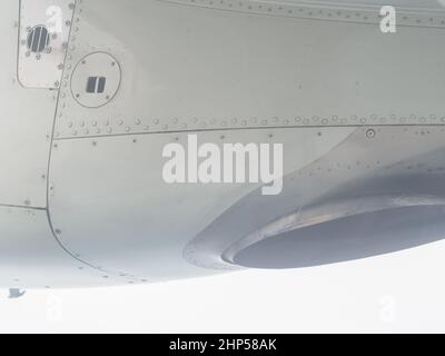 Fragment des Mini-Flugzeug-Flügels mit Nähten und Metallschrauben. Nahaufnahme. Blick aus dem Flugzeugfenster Stockfoto