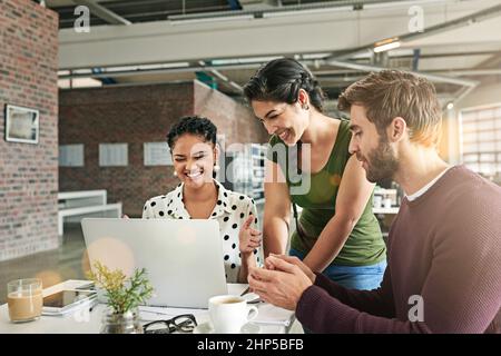 Einfachere Problemlösung dank Technologie. Aufnahme eines Teams von Kollegen, die in einem modernen Büro zusammen einen Laptop benutzen. Stockfoto