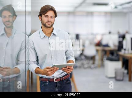 HES ein selbstbewusster junger Geschäftsmann. Porträt eines hübschen jungen Geschäftsmannes, der in seinem Büro steht. Stockfoto